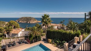 Un espace piscine comprenant des chaises longues, une petite piscine et une vue sur la mer et une île rocheuse.