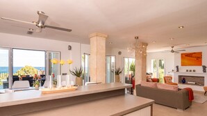 Une cuisine moderne dotée d’un grand îlot central, d’un coin repas offrant une vue agréable et d’un salon avec cheminée.
