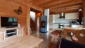 Un interior de madera con televisor, armarios, banca y zona de cocina.