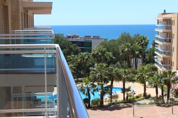 A resort with a pool, palm trees, and a view of the sea. - Apartment with pool and terrace overlooking the sea (Salou)