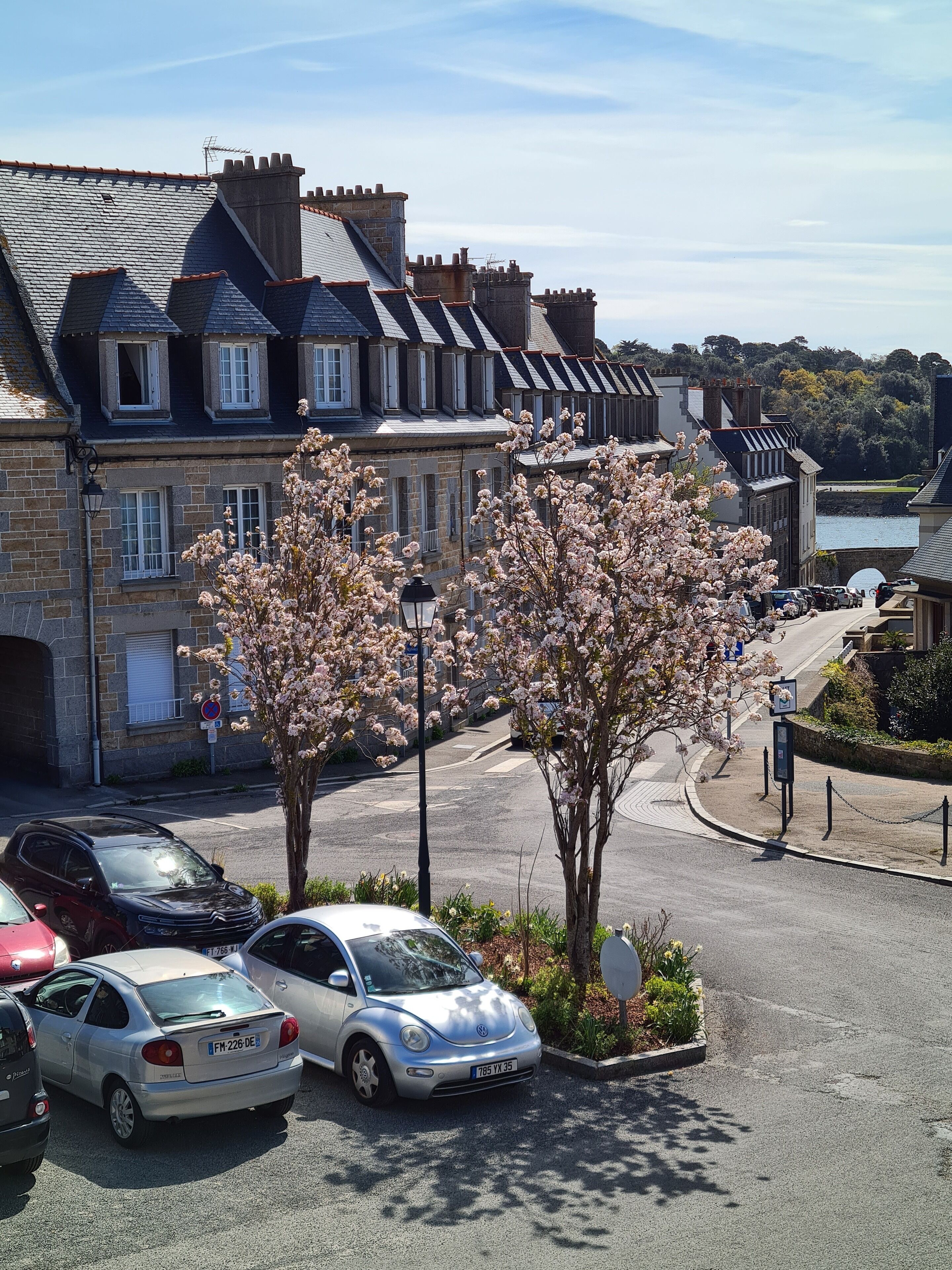 A parking area with cars, a street lamp, and a building with stone walls and multiple windows.