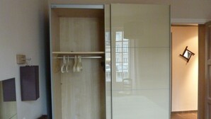 A room with a sliding door closet, a coat rack with hangers, a small mirror on the wall, and a chair. - St Malo F3 62m² Alet Solidor peninsula, sea 50m, wifi, garden, secure parking (ST MALO)