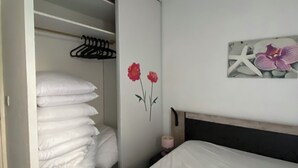 A bedroom with a bed, a closet with hanging clothes, and a wall decoration. - Modern apartment breathtaking sea view and waterfront (Sète)