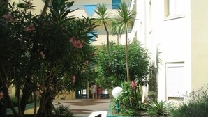 A courtyard with tiled flooring, potted plants, and a building with balconies. - Modern apartment breathtaking sea view and waterfront (Sète)