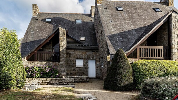 A stone building with a sloped roof, a wooden deck, and a white door. - Flat with seaview - 50m from beach- 3/4 persons (Carnac)