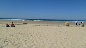 A beach with people sitting and walking, umbrellas, and a clear sky. - Flat with seaview - 50m from beach- 3/4 persons (Carnac)