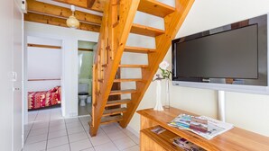 A room with a wooden staircase, a flat-screen TV, and a wooden desk with magazines. - Flat with seaview - 50m from beach- 3/4 persons (Carnac)