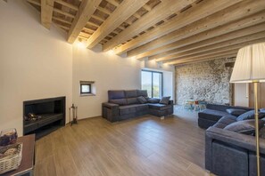 A spacious living area with a fireplace, sofas, and a stone wall.