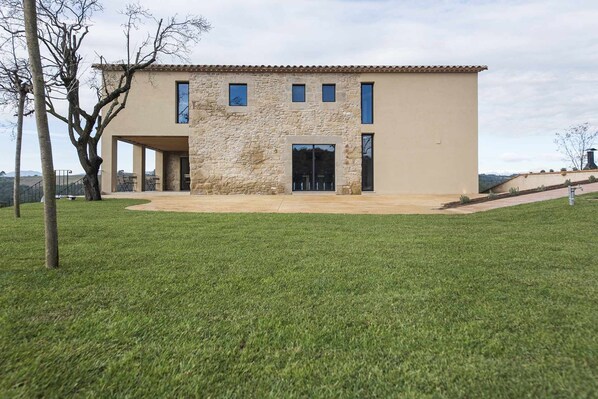 A modern two-story house with a stone facade, large windows, and a covered patio.