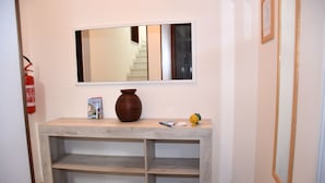 A hallway with a wooden console table, a vase, a framed mirror, and a fire extinguisher. - ONLY 150 METERS FROM THE SEA OF S. SALENTO- MARIA DI LEUCA- PESCOLUSE-Torrevado (Leuca)