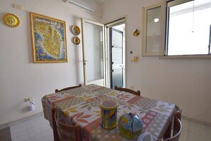 Ein Essbereich mit Tisch, Stühlen, einer dekorativen Vase und einer Karte an der Wand.