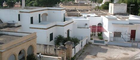 Zona residencial con edificios blancos, una verja roja y una torre al fondo.