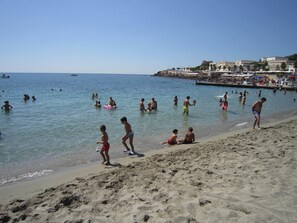 Ein Strand mit badenden Personen und Spaziergängern am Ufer.