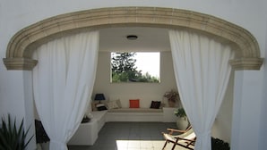 A sunlit patio area with a stone bench, a cushioned seating area, and a view of trees through a window. - ONLY 150 METERS FROM THE SEA OF S. SALENTO- MARIA DI LEUCA- PESCOLUSE-Torrevado (Leuca)