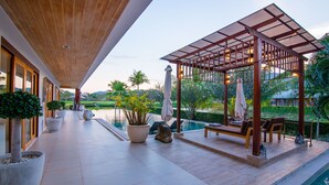 A covered outdoor area with a pool, seating, and potted plants. - Golf Resort /Villa in Hua Hin, Palm Hills Golf Resort (Tambon Hua Hin)