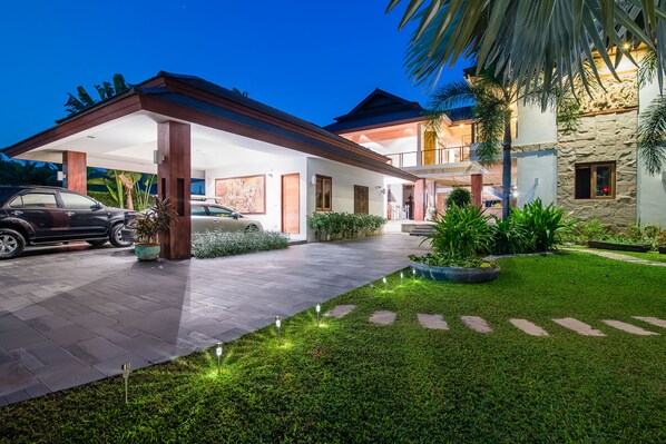 A modern house with a covered driveway, a stone exterior, and a well-maintained lawn.