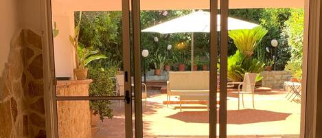 A room with a sliding glass door leading to an outdoor patio area with a table, chairs, and potted plants.