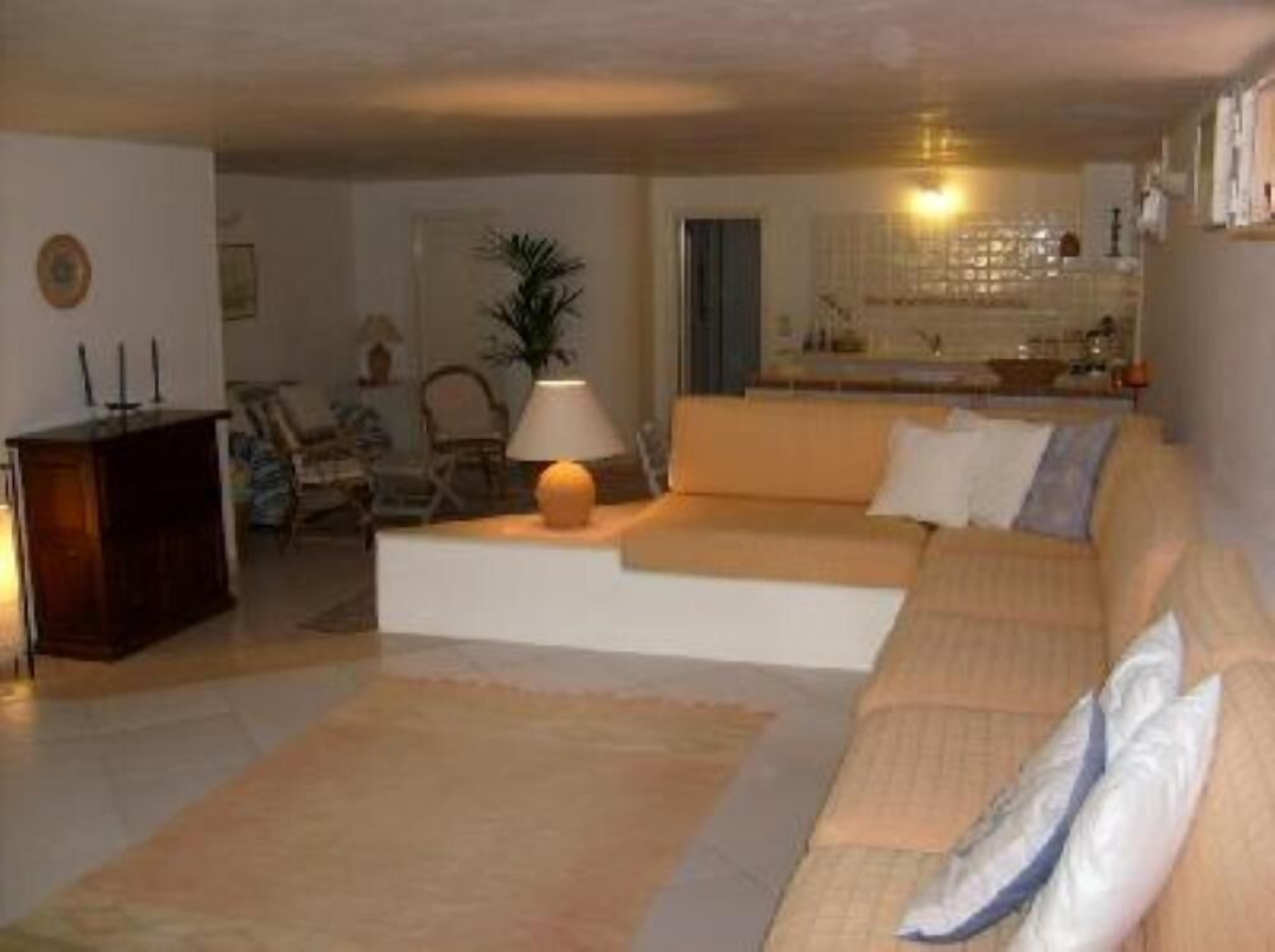 A living room with a sofa, a lamp, and a small table. There is a door leading to another room.