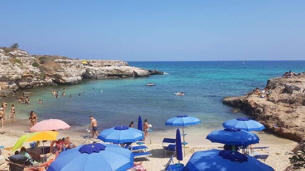 A beach with clear turquoise water, rocky cliffs, and several people swimming and sunbathing. - Greek/Mediterranean style villa of 200 sqm, with elegant interiors, family friendly (Pilone)