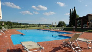 A swimming pool with lounge chairs and a pergola.
