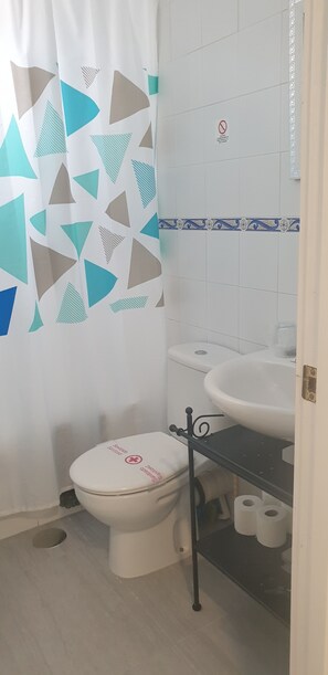 Een badkamer met toilet, wastafel en douchegordijn.