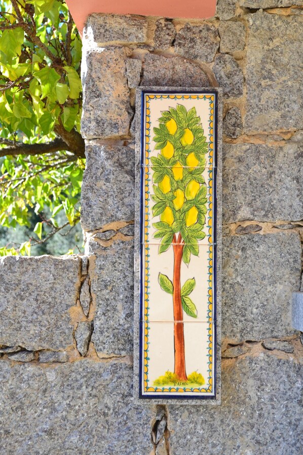 A stone wall with a tiled artwork of a lemon tree.