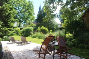 An outdoor patio with wooden furniture and a view of a church steeple.