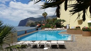 Ein Poolbereich mit Liegestühlen, einem Rettungsring und einem Schild mit der Aufschrift 'Pestana Bay'.