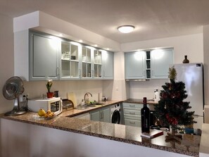 Uma cozinha moderna com bancadas de granito, micro-ondas embutido e uma garrafa de vinho.