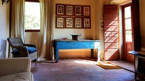 Una habitación con una silla de mimbre, una mesa azul y una puerta que da al exterior.