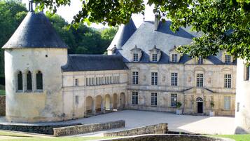 Een historisch gebouw met een binnenplaats, een toren en een groot centraal gebouw met meerdere ramen en bogen.