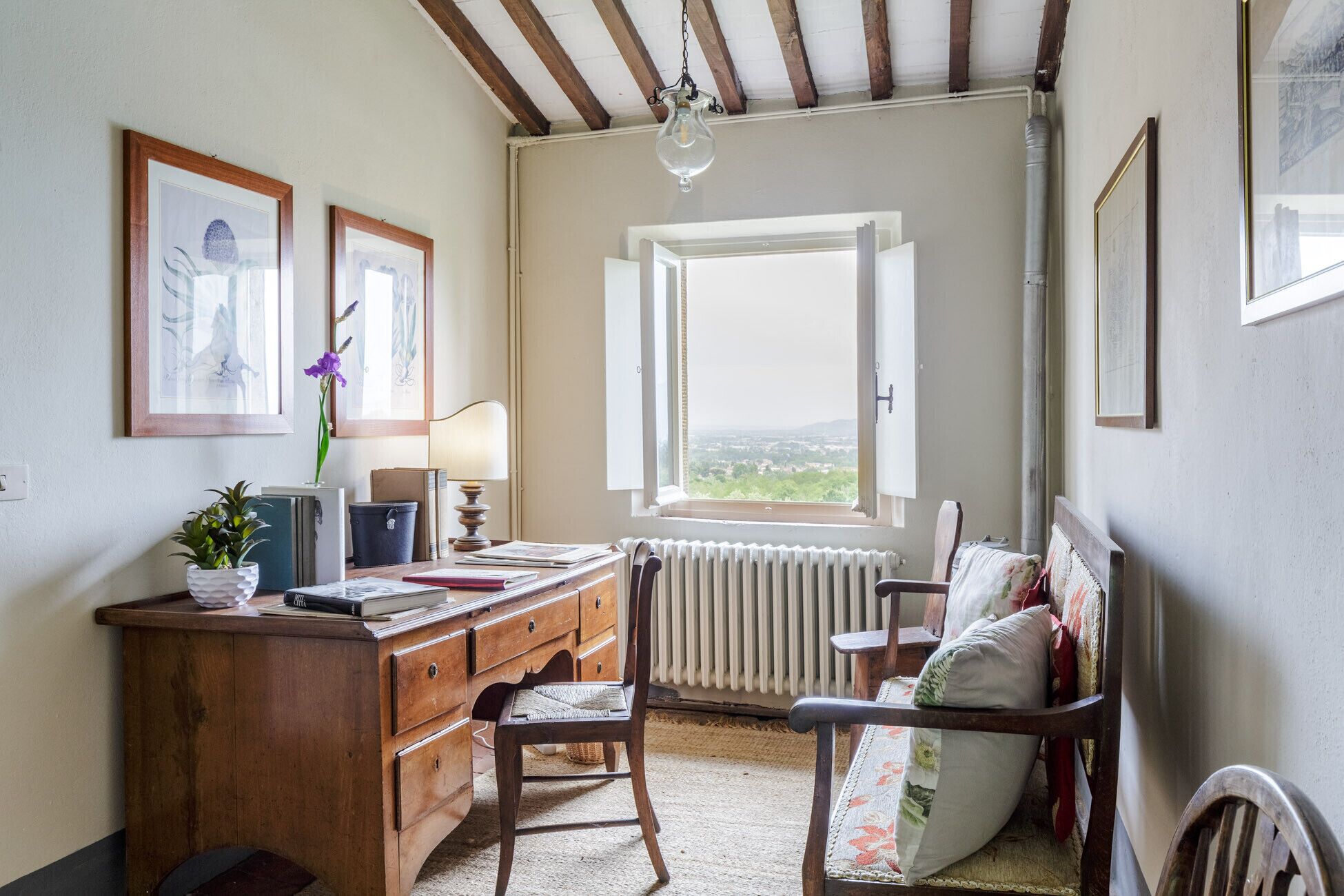 Une pièce agréable aménagée en bureau, avec un bureau en bois, une chaise, un radiateur et une fenêtre dont le volet est ouvert.