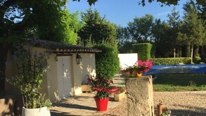 A garden area with a stone pathway, potted plants, and a small building with a tiled roof. - MAS with swimming pool 5 minutes from Saint Remy de Provence (Tarascon)