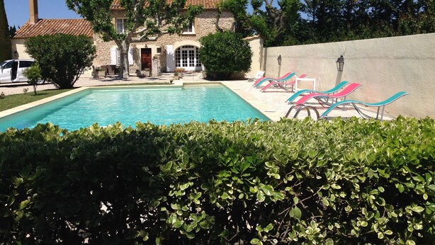 A pool area with lounge chairs, a stone building with a tiled roof, and surrounding greenery. - MAS with swimming pool 5 minutes from Saint Remy de Provence (Tarascon)