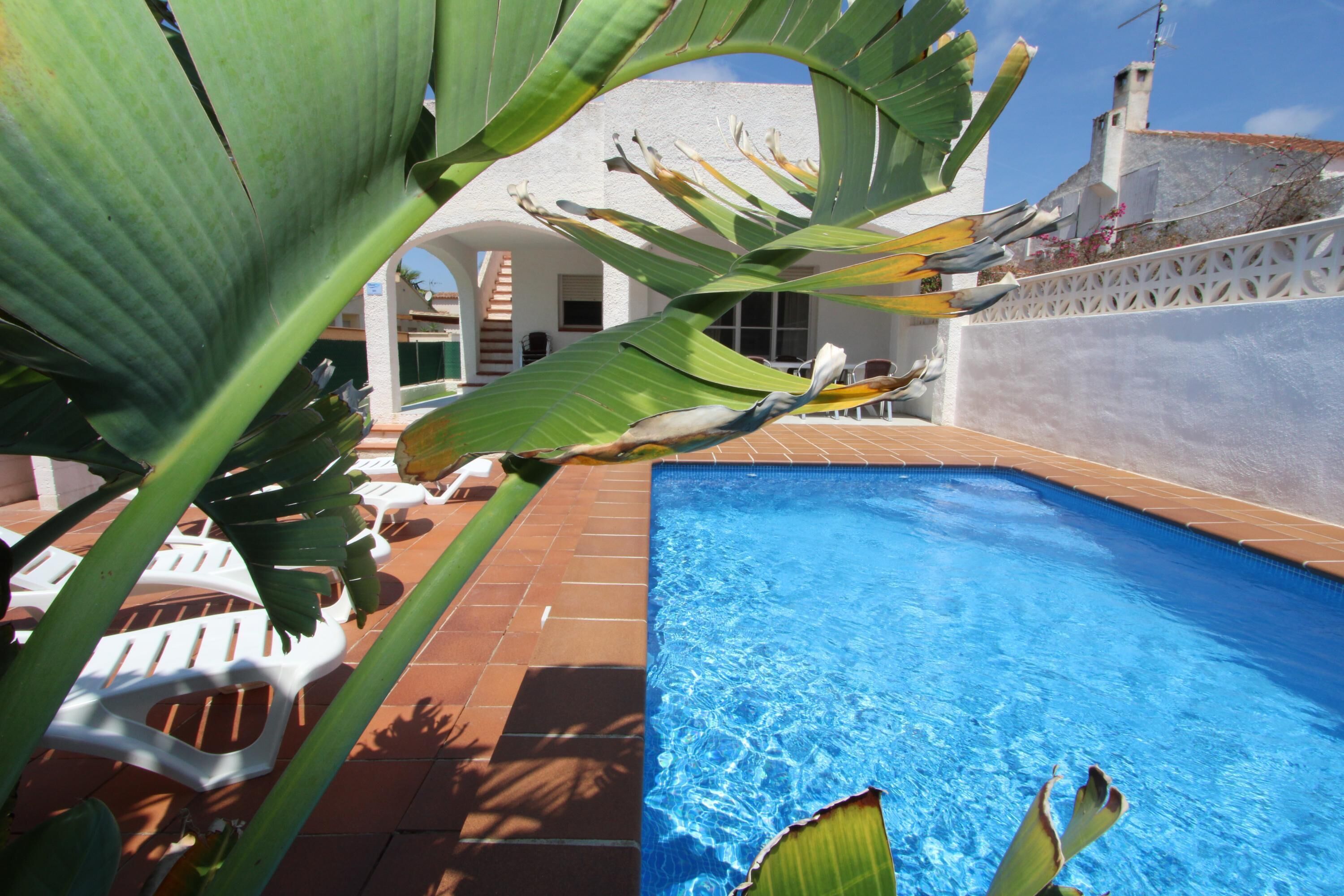 A swimming pool with white lounge chairs and a white building in the background.