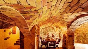 Un interior con arcos de piedra y una mesa con sillas.