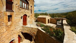 Un edificio de piedra con una puerta roja y una estructura pequeña adosada.