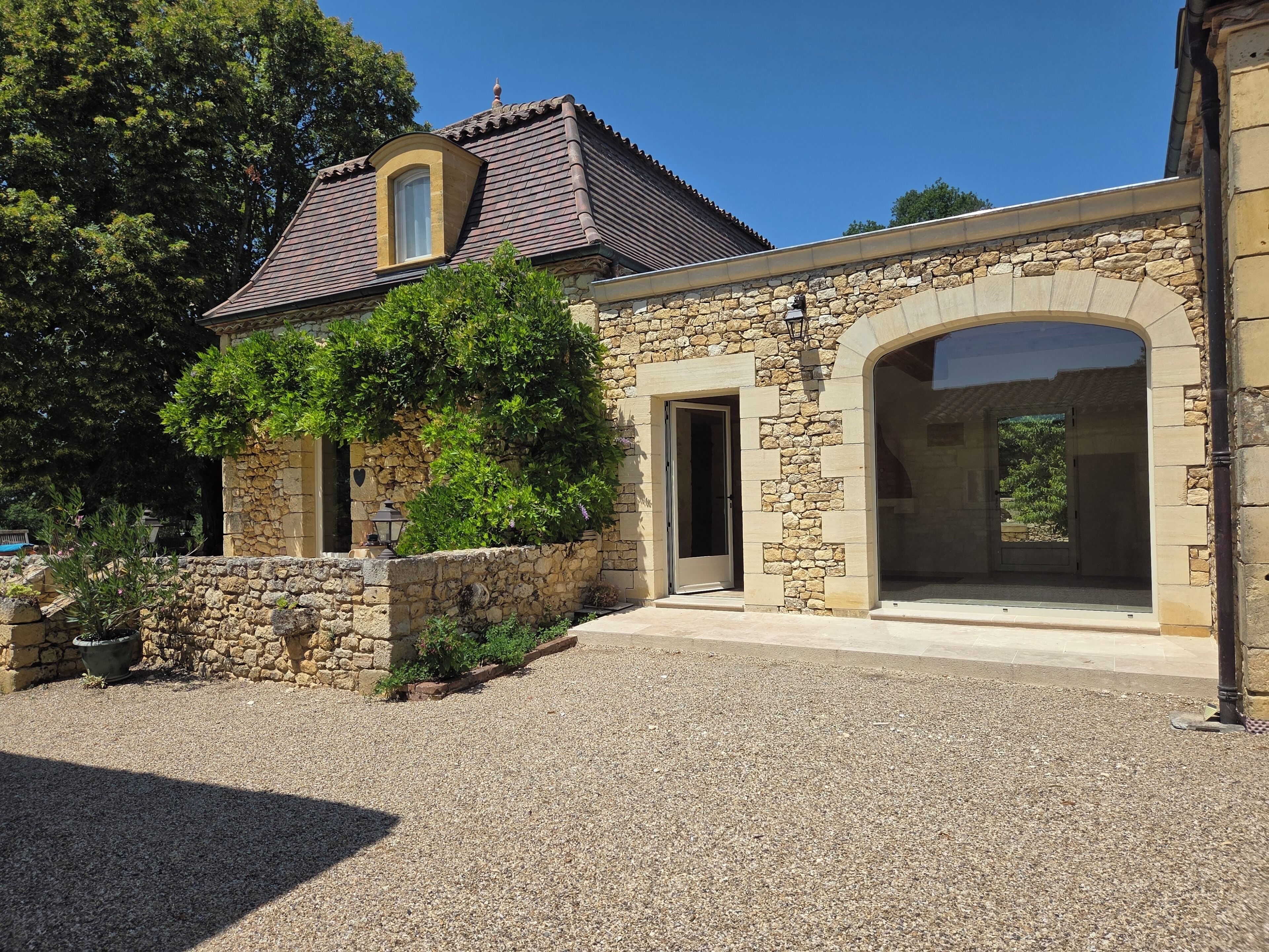 A stone building with a tiled roof, a doorway, and a large window.