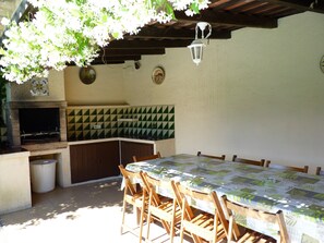An outdoor patio with a table and chairs, a grill, and a hanging lantern.