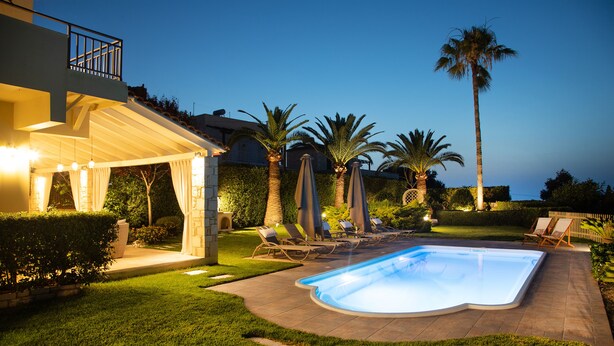 A backyard with a swimming pool, lounge chairs, palm trees, and a covered patio area. - Malena Villa with Private Pool | Walking distance to beach & restaurants (Rethymno)