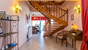 A staircase with wooden railings leading to an upper floor. There is a dining area with a table and chairs visible in the background. - Malena Villa with Private Pool | Walking distance to beach & restaurants (Rethymno)