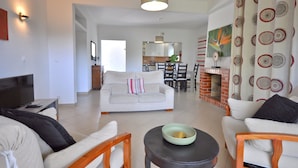 A living room with a sofa, chairs, a coffee table, a TV, and a fireplace. - Delightful single-storey villa, private pool, free air conditioning and wifi (Vilamoura)