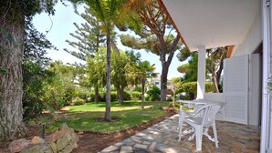 A patio with stone flooring, white chairs, and a table. - Delightful single-storey villa, private pool, free air conditioning and wifi (Vilamoura)