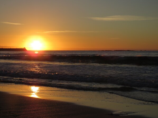 A sunset over a beach with waves. - Holiday Cottage in Gulval Penzance Cornwall (Penzance Cornwall)