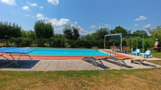 Ein Schwimmbad mit Tischtennisplatte, Liegestühlen und Grill.
