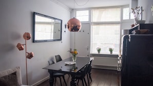 En matplats med ett bord, stolar, en vas med blommor, en spegel och en hängande lampa.