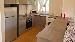 Cocina compacta equipada con refrigerador, microondas, horno y lavadora.