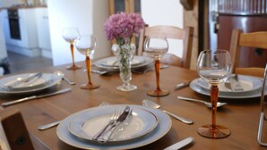 A dining table set with plates, cutlery, and wine glasses, with a vase of flowers in the center. - Luxury character Cottage in a popular Village location in Central Northumberland (Morpeth)