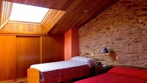 A room with a sloped ceiling, wooden walls, a stone wall, two beds, and a skylight. - Aunt Matea's House for 7 people (Migueláñez)