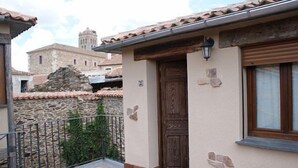 A building with a stone wall, a wooden door, and a window with a curtain. - Aunt Matea's House for 7 people (Migueláñez)